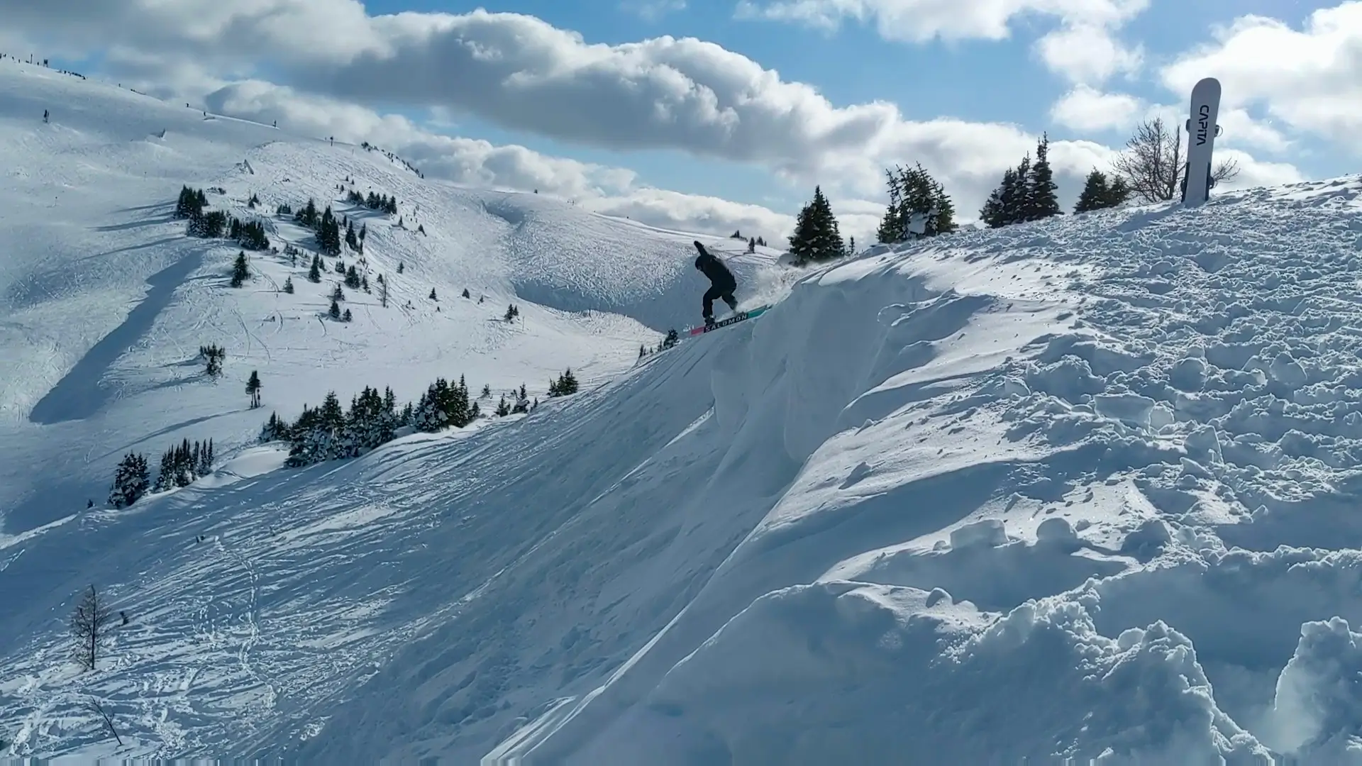Slopestory founder Chad riding off a cliff drop on a backcountry slope under a big sky